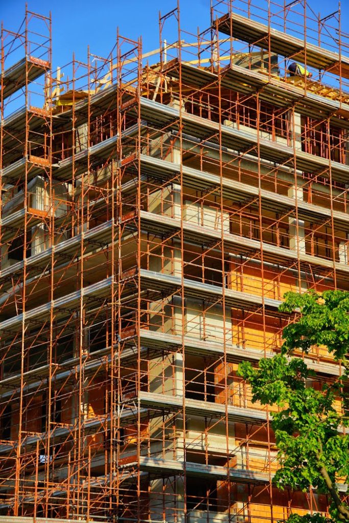 A multi-story building under construction with scaffolding on a sunny day.
